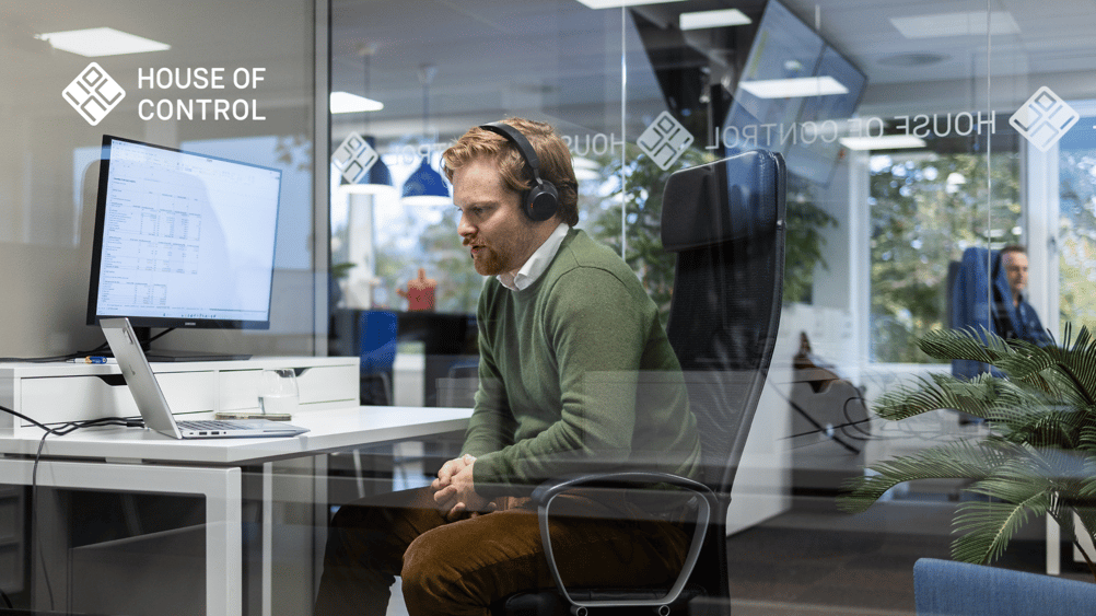 A house of control employee working in an office, wearing a headset.