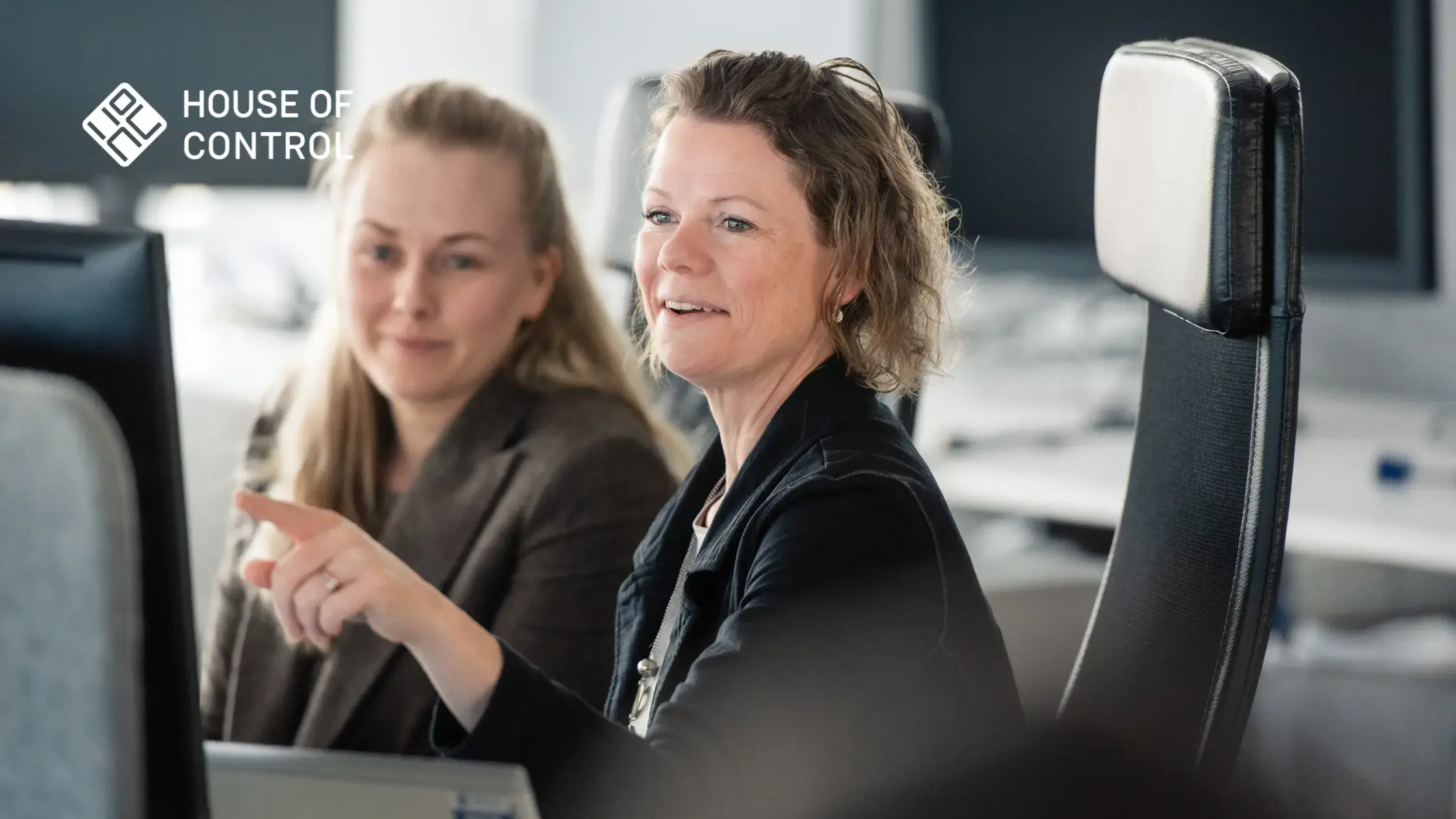 Two colleagues working at House of Control pointing at a screen while sitting down